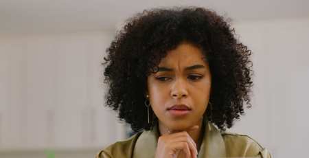 Shot of a young woman looking confused while using a laptop at home