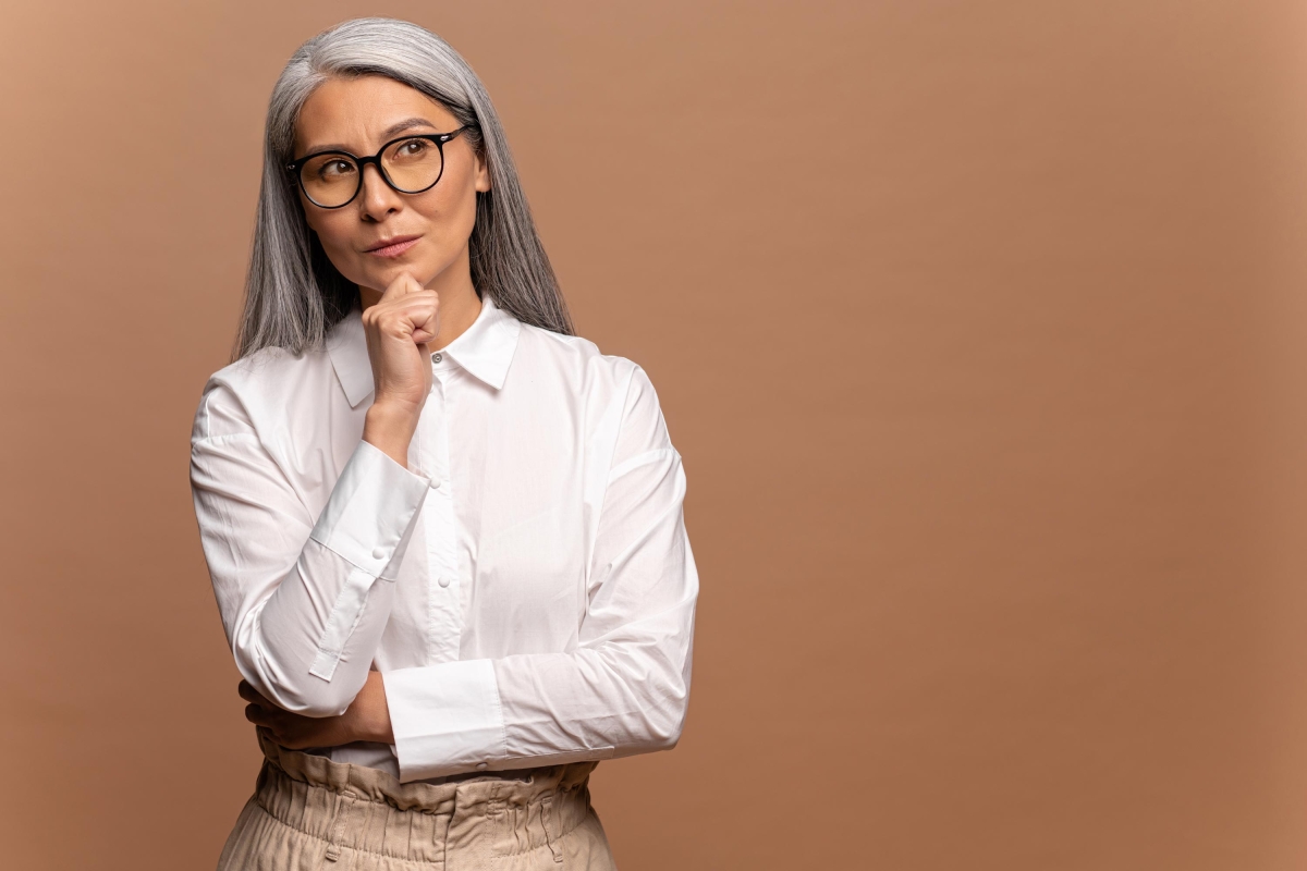 Smart and thoughtful mature woman holding her chin and looking uncertain doubtful.