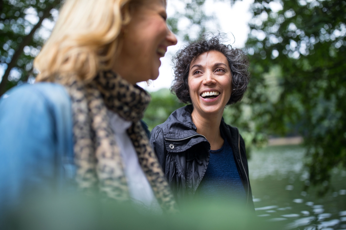 Happy woman looking at friend in forest